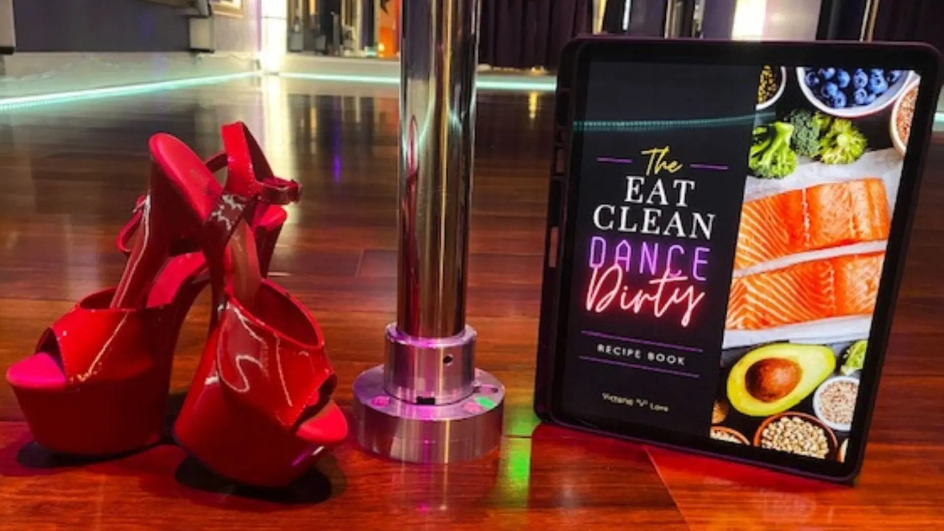 Red platform pole dancing heels next to dance pole and Eat Clean Dance Dirty recipe book at PoleKittens Fitness studio in Cincinnati